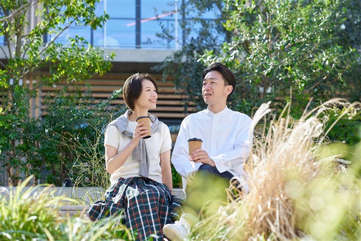 公園でコーヒーを片手に話すカップル