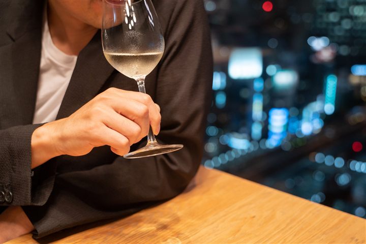 夜景の見えるバーでグラスを傾ける男性