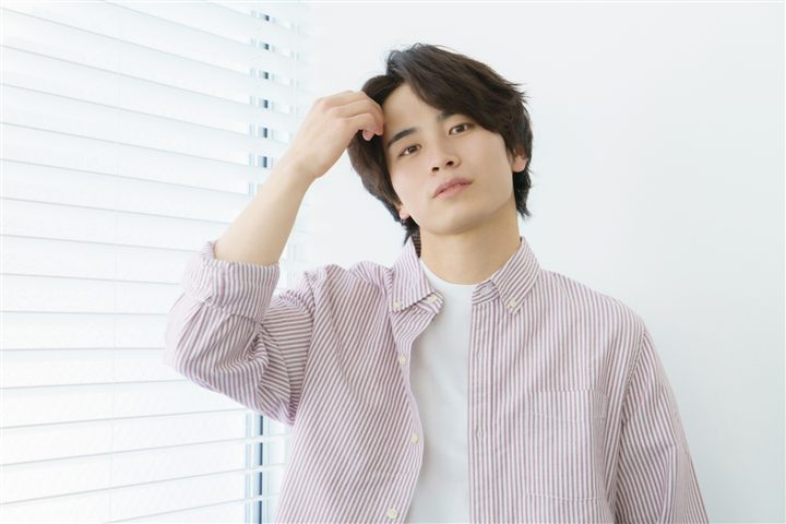 窓際に立つカジュアルなシャツの男性